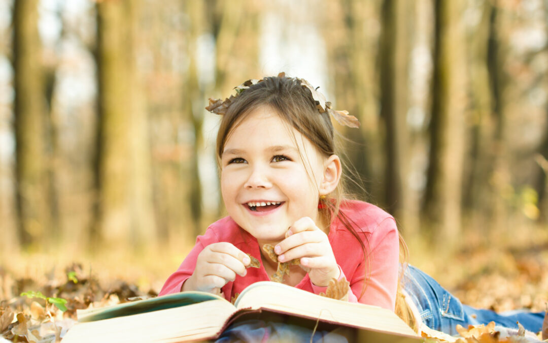 Little girl is reading a book outdoors