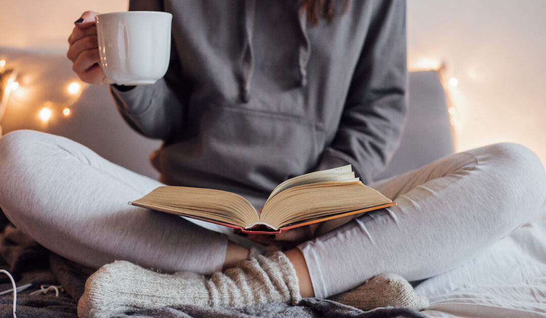 Woman on the bed with book and coffee