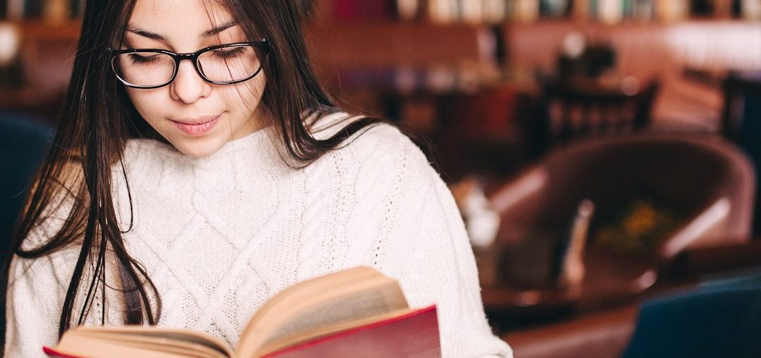 young student girl reading book in a library