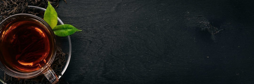 A cup of black tea on a wooden background. Top view. Copy space.
