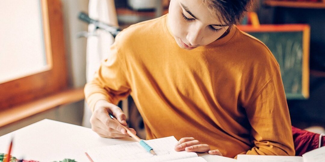 Young boy sitting in his room, bored, doing homework
